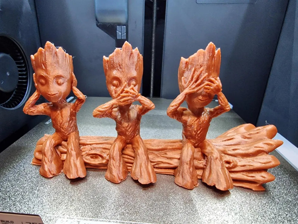 Drei Baby Groot auf Baumstamm